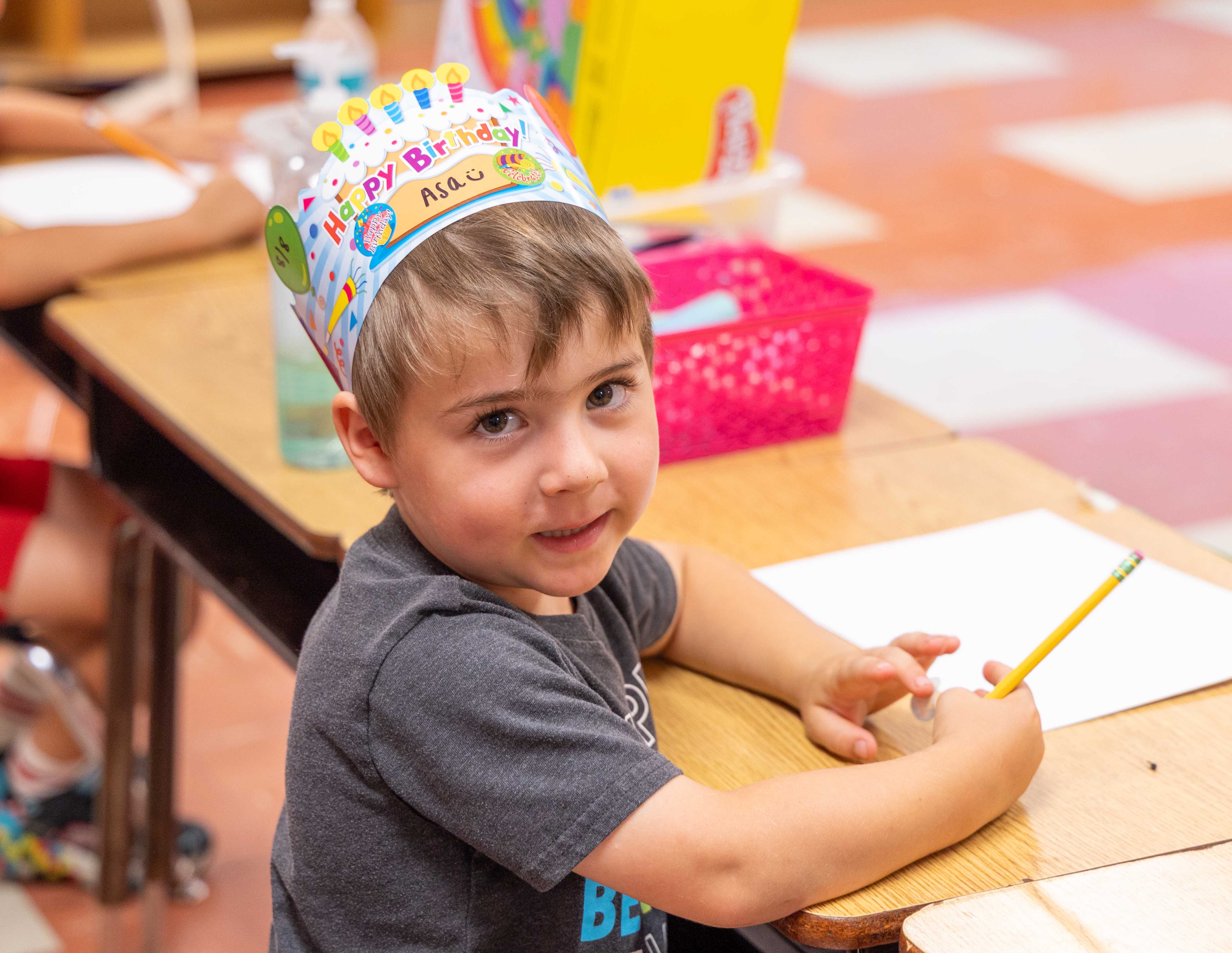A young student smiles wearing a birthday crown
